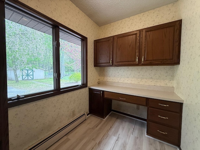 6035 W Trails End Rd, Ludington, MI 49431 - unfurnished office featuring baseboard heating, built in study area, light wood-style flooring, wallpapered walls, and a textured ceiling