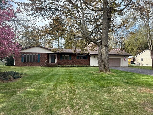 6035 W Trails End Rd, Ludington, MI 49431 - ranch-style house with driveway, a garage, and a front lawn