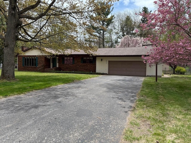 6035 W Trails End Rd, Ludington, MI 49431 - view of front facade featuring asphalt driveway, a garage, and a front lawn