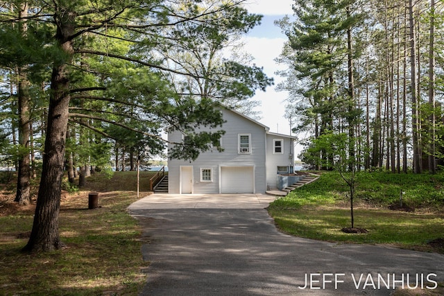 6789 W 76th St, Baldwin, MI 49304 - traditional-style house with stairs, asphalt driveway, and a garage
