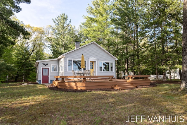 6789 W 76th St, Baldwin, MI 49304 - view of front facade with a deck, a front yard, a chimney, and view of scattered trees