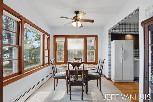 6789 W 76th St, Baldwin, MI 49304 - dining area featuring a baseboard radiator, a ceiling fan, wood finished floors, and baseboards