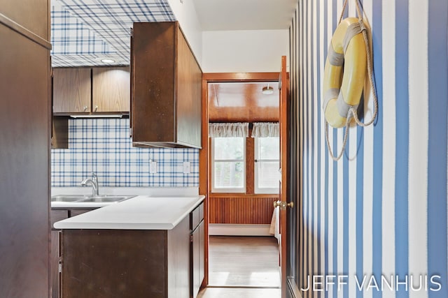 6789 W 76th St, Baldwin, MI 49304 - kitchen with a baseboard radiator, light countertops, wallpapered walls, a sink, and light wood-style floors
