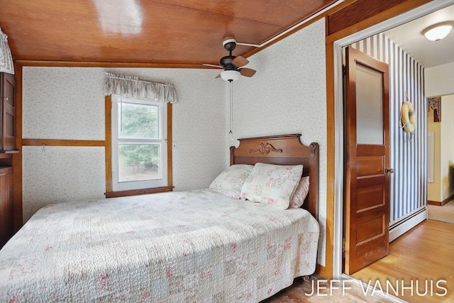 6789 W 76th St, Baldwin, MI 49304 - bedroom featuring wallpapered walls, a baseboard radiator, wood finished floors, and ceiling fan