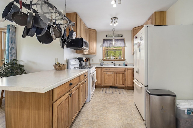 5729 N Bass Lake Rd, Irons, MI 49644 - kitchen with white appliances, a sink, light countertops, light floors, and a peninsula