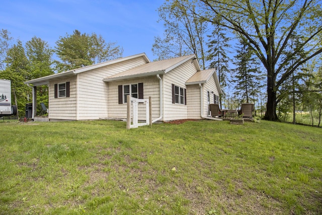 5729 N Bass Lake Rd, Irons, MI 49644 - back of property with a yard and metal roof