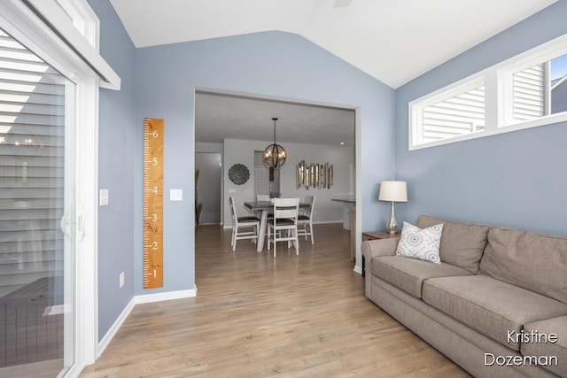 12036 Harvest Home Dr, Lowell, MI 49331 - living area featuring vaulted ceiling, light wood-style floors, a chandelier, and baseboards