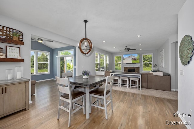 12036 Harvest Home Dr, Lowell, MI 49331 - dining area featuring a ceiling fan, light wood-style floors, a fireplace, plenty of natural light, and vaulted ceiling