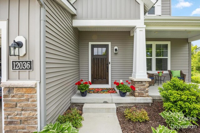 12036 Harvest Home Dr, Lowell, MI 49331 - doorway to property with covered porch and board and batten siding