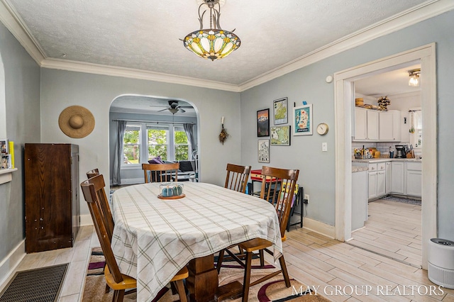 1212 Johnston St SE, Grand Rapids, MI 49507 - dining space with arched walkways, a ceiling fan, light wood-style flooring, crown molding, and baseboards