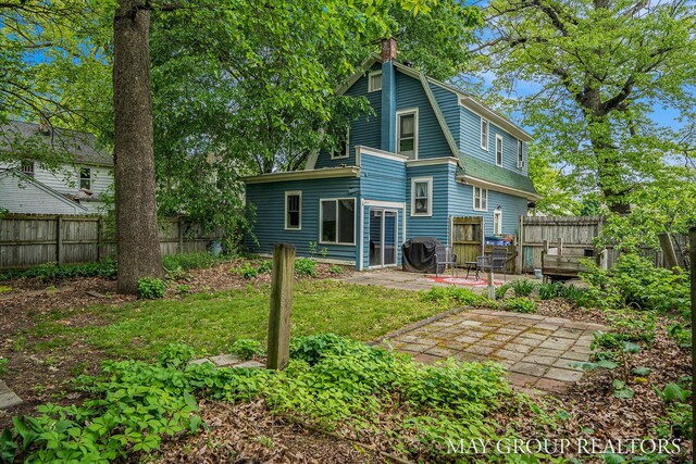 1212 Johnston St SE, Grand Rapids, MI 49507 - back of house featuring a patio, a fenced backyard, a chimney, and a gambrel roof