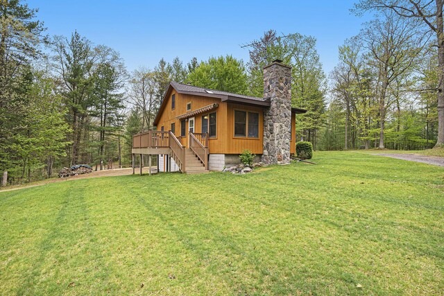 4900 N Railroad Ave, Pentwater, MI 49449 - view of side of home with a chimney, driveway, a lawn, a deck, and an attached garage
