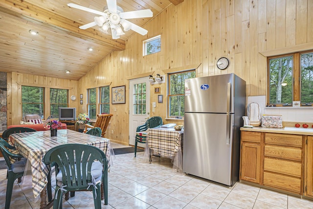 4900 N Railroad Ave, Pentwater, MI 49449 - dining area with healthy amount of natural light, light tile patterned floors, wood walls, high vaulted ceiling, and a ceiling fan