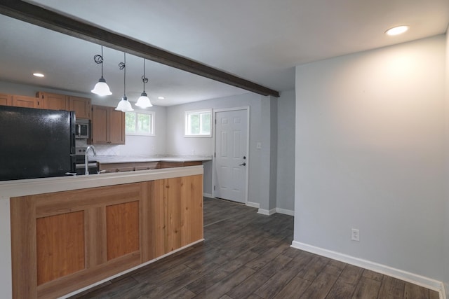 879 Carberry Rd, Niles, MI 49120 - kitchen featuring freestanding refrigerator, stainless steel microwave, dark wood finished floors, light countertops, and hanging light fixtures