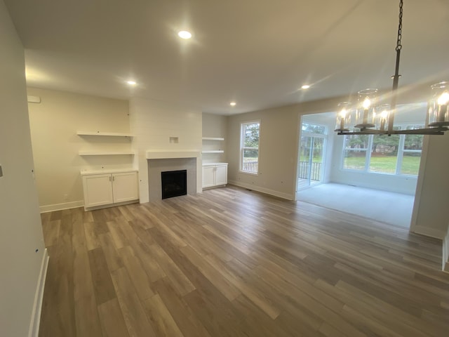 2583 Ravines Trail Dr SW, Byron Center, MI 49315 - unfurnished living room featuring baseboards, wood finished floors, a fireplace, recessed lighting, and a chandelier