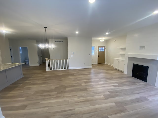 2583 Ravines Trail Dr SW, Byron Center, MI 49315 - unfurnished living room featuring a fireplace, baseboards, recessed lighting, light wood-type flooring, and a chandelier