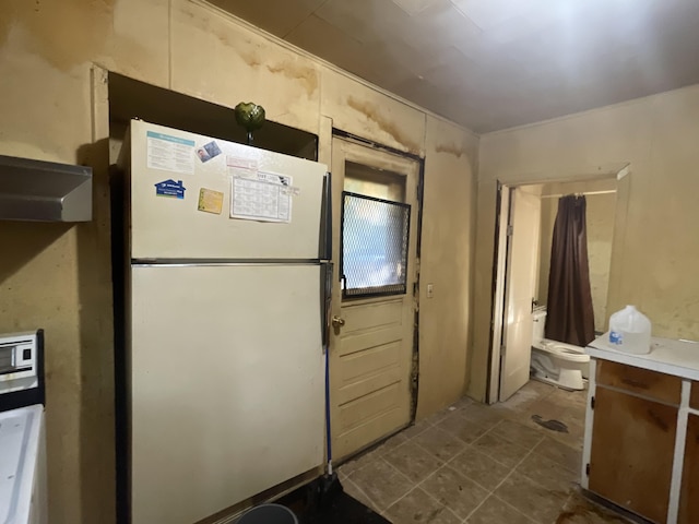 2645 Howden St, Muskegon Heights, MI 49444 - kitchen with freestanding refrigerator and dark tile patterned floors