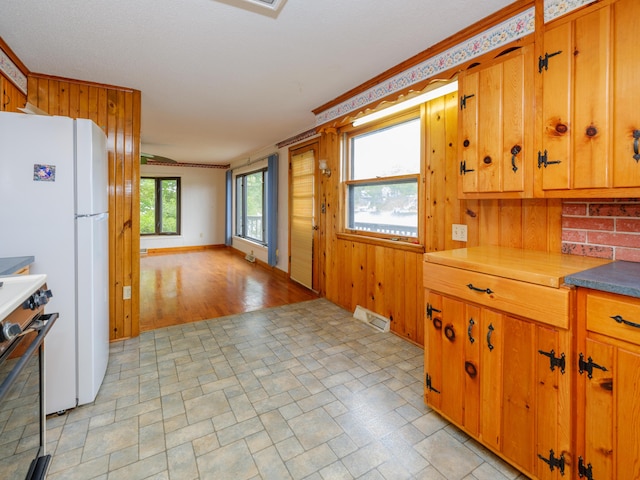12391 Sunset Dr, Plainwell, MI 49080 - kitchen featuring range, freestanding refrigerator, brown cabinets, open floor plan, and wood walls