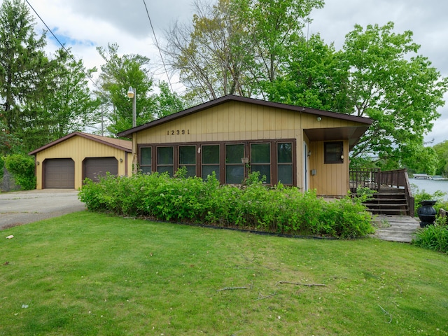 12391 Sunset Dr, Plainwell, MI 49080 - view of front of property with a front lawn, concrete driveway, a garage, and a wooden deck