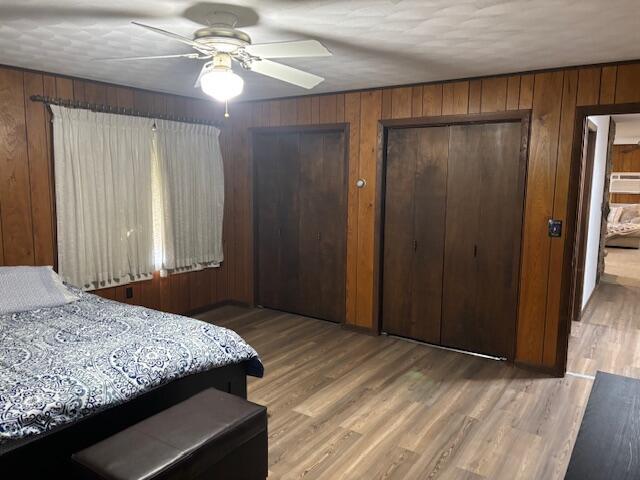 18593 30th Ave, Barryton, MI 49305 - bedroom featuring wood walls, wood finished floors, multiple closets, and ceiling fan
