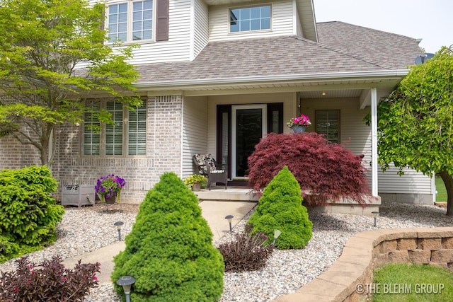 1705 Fritz St, Marne, MI 49435 - view of exterior entry featuring covered porch, a shingled roof, and brick siding