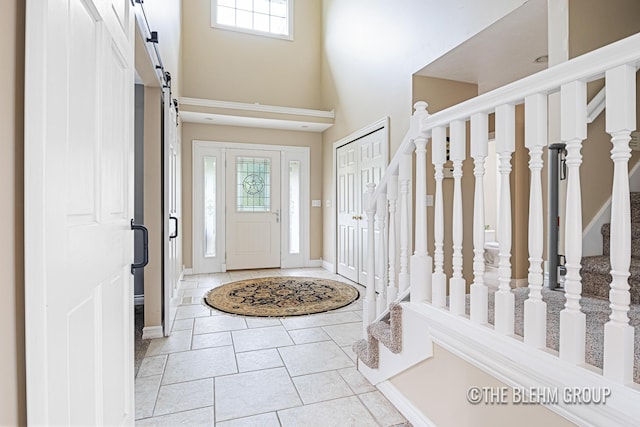 1705 Fritz St, Marne, MI 49435 - entrance foyer with a barn door, plenty of natural light, a towering ceiling, light tile patterned flooring, and stairway
