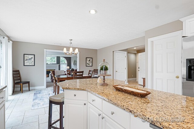 1705 Fritz St, Marne, MI 49435 - kitchen with white cabinetry, a breakfast bar, a chandelier, pendant lighting, and light stone countertops