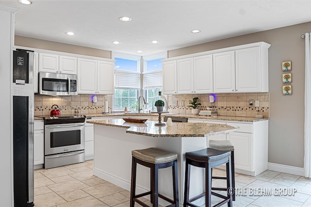 1705 Fritz St, Marne, MI 49435 - kitchen with stainless steel appliances, a breakfast bar area, tasteful backsplash, a center island, and recessed lighting