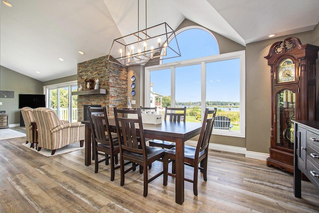 14776 Park Ct, Grand Haven, MI 49417 - dining space with lofted ceiling, wood finished floors, baseboards, a chandelier, and a stone fireplace