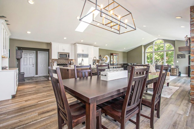 14776 Park Ct, Grand Haven, MI 49417 - dining room featuring wood finished floors, lofted ceiling, recessed lighting, and a chandelier