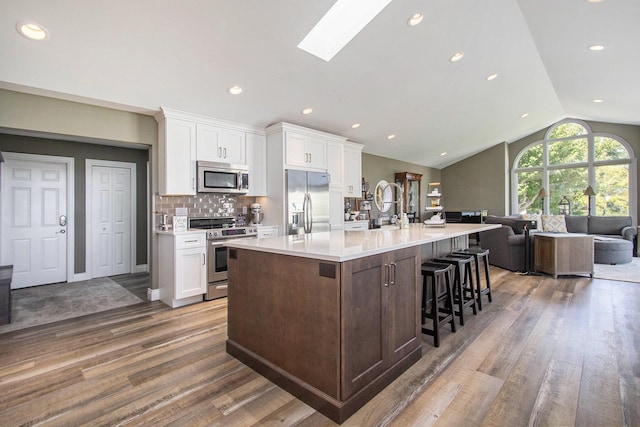 14776 Park Ct, Grand Haven, MI 49417 - kitchen with appliances with stainless steel finishes, wood finished floors, white cabinetry, light countertops, and lofted ceiling