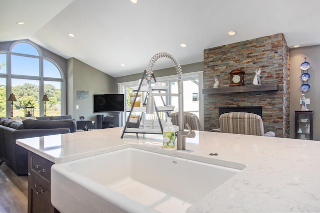 14776 Park Ct, Grand Haven, MI 49417 - kitchen featuring open floor plan, vaulted ceiling, healthy amount of natural light, a stone fireplace, and light stone countertops