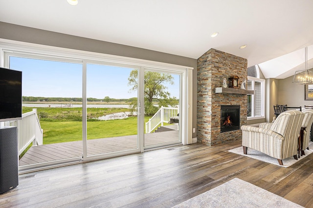 14776 Park Ct, Grand Haven, MI 49417 - living area featuring a water view, vaulted ceiling, wood finished floors, a large fireplace, and a chandelier
