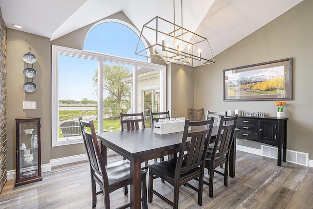 14776 Park Ct, Grand Haven, MI 49417 - dining space with wood finished floors, a chandelier, baseboards, and high vaulted ceiling