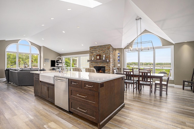 14776 Park Ct, Grand Haven, MI 49417 - kitchen featuring vaulted ceiling, open floor plan, dishwasher, a sink, and a stone fireplace