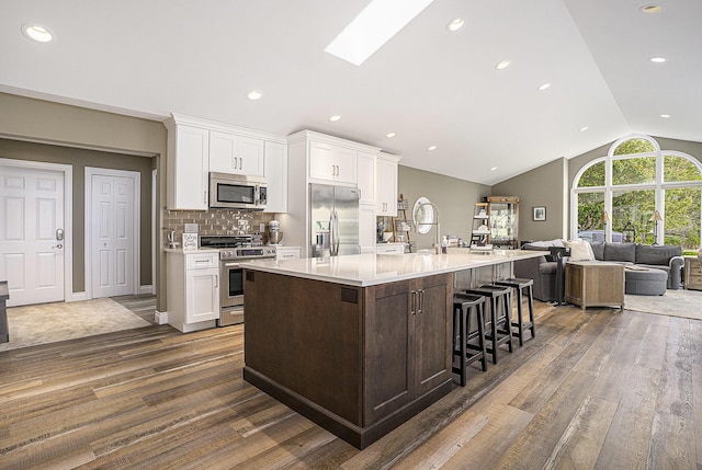 14776 Park Ct, Grand Haven, MI 49417 - kitchen featuring appliances with stainless steel finishes, dark wood-style floors, light countertops, vaulted ceiling, and white cabinets