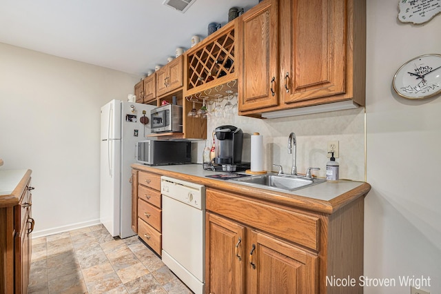 4124 Cummings Ct NW, Grand Rapids, MI 49534 - kitchen featuring white appliances, a sink, brown cabinets, stone finish floors, and light countertops