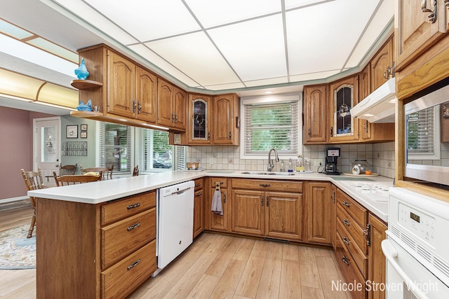 4124 Cummings Ct NW, Grand Rapids, MI 49534 - kitchen with white appliances, a sink, brown cabinets, a peninsula, and under cabinet range hood