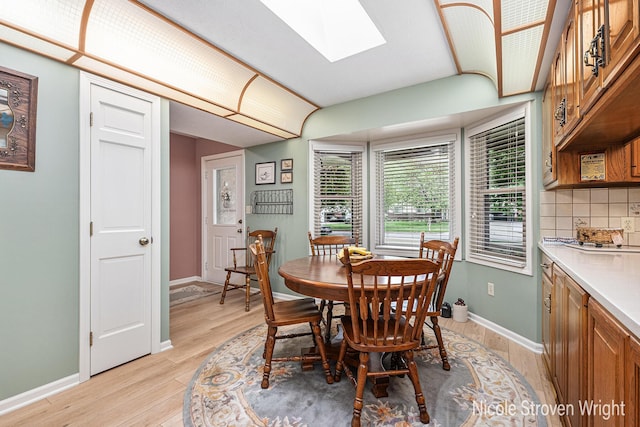 4124 Cummings Ct NW, Grand Rapids, MI 49534 - dining room featuring light wood-style flooring, a skylight, and baseboards