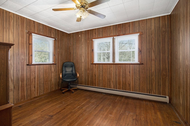 7034 W Dewey Rd, Ludington, MI 49431 - empty room with wood-type flooring, baseboard heating, wooden walls, and ceiling fan