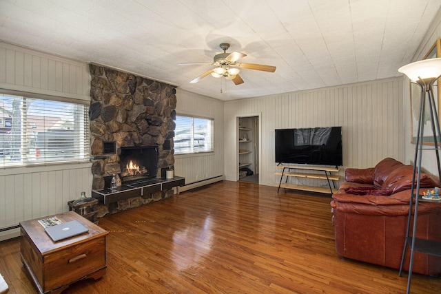 7034 W Dewey Rd, Ludington, MI 49431 - living area featuring wood finished floors, ceiling fan, a stone fireplace, wood walls, and ornamental molding