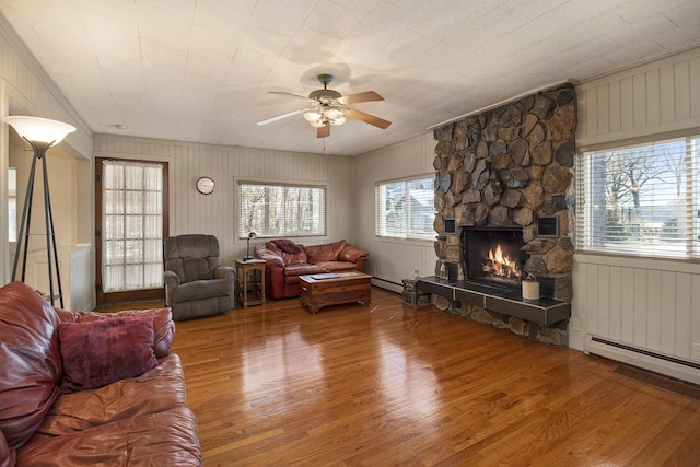 7034 W Dewey Rd, Ludington, MI 49431 - living room with wood finished floors, a fireplace, ceiling fan, baseboard heating, and crown molding