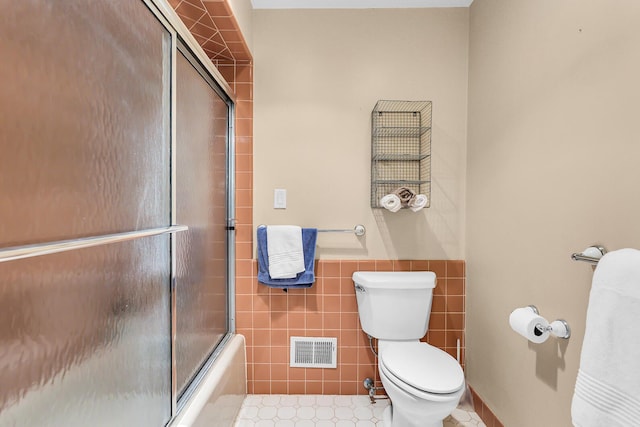 5340 Squires Manor Rd, Jackson, MI 49201 - bathroom featuring toilet, tile walls, bath / shower combo with glass door, wainscoting, and tile patterned flooring