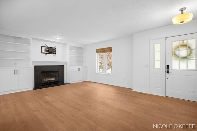 7745 Worthing Ct SW, Byron Center, MI 49315 - unfurnished living room featuring light wood finished floors, a tiled fireplace, and built in features