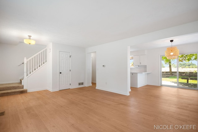 7745 Worthing Ct SW, Byron Center, MI 49315 - unfurnished living room featuring light wood-type flooring and stairs