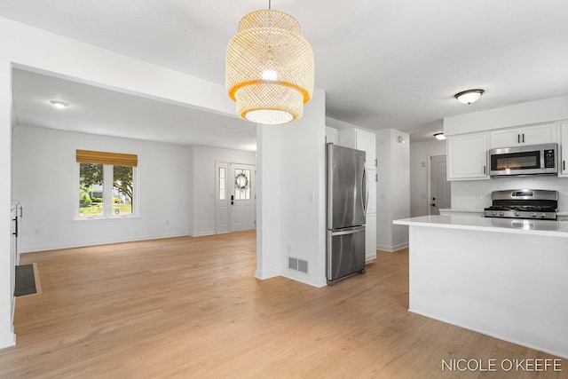 7745 Worthing Ct SW, Byron Center, MI 49315 - kitchen featuring appliances with stainless steel finishes, white cabinets, light countertops, backsplash, and light wood-style floors