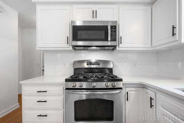 7745 Worthing Ct SW, Byron Center, MI 49315 - kitchen with stainless steel appliances, white cabinets, decorative backsplash, wood finished floors, and light countertops