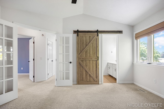 7745 Worthing Ct SW, Byron Center, MI 49315 - unfurnished bedroom with french doors, carpet flooring, lofted ceiling, a barn door, and connected bathroom
