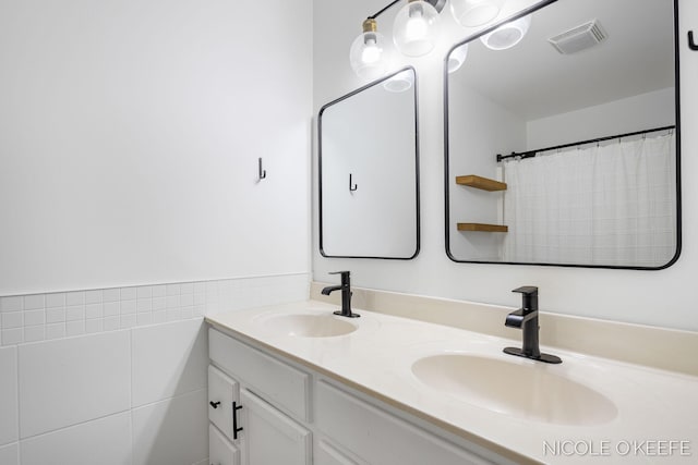 7745 Worthing Ct SW, Byron Center, MI 49315 - bathroom featuring double vanity, tile walls, and a wainscoted wall