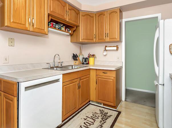 23165 Church St, Oak Park, MI 48237 - kitchen with white appliances, a sink, light countertops, light wood finished floors, and brown cabinets